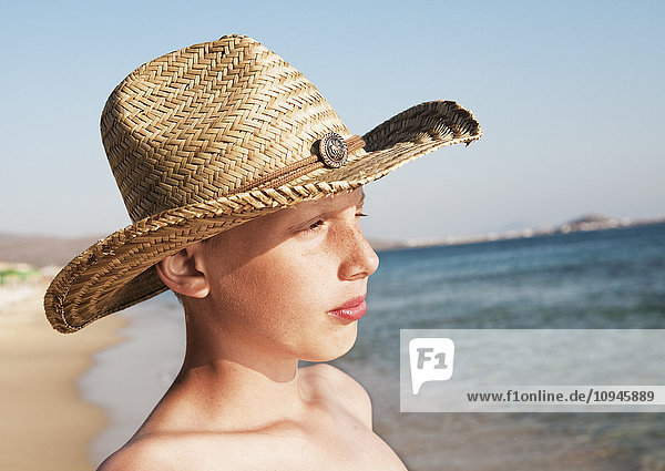 Portrait of teenage boy wearing straw hat on beach
