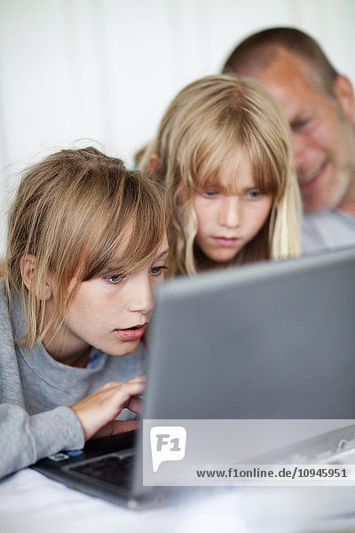 Girls with father using laptop