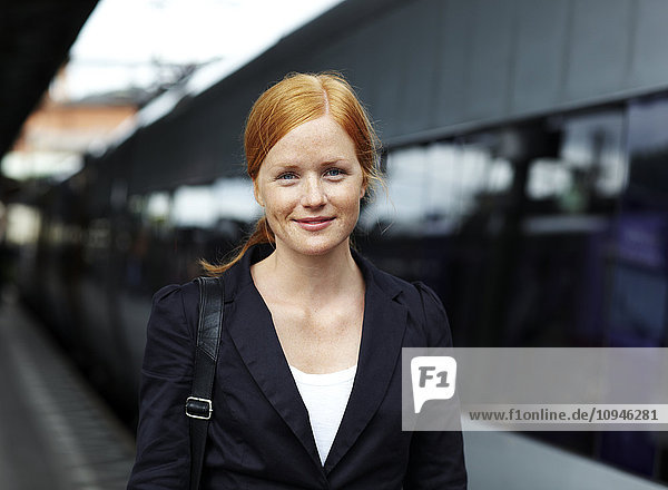 Porträt einer jungen lächelnden Frau auf dem Bahnhof