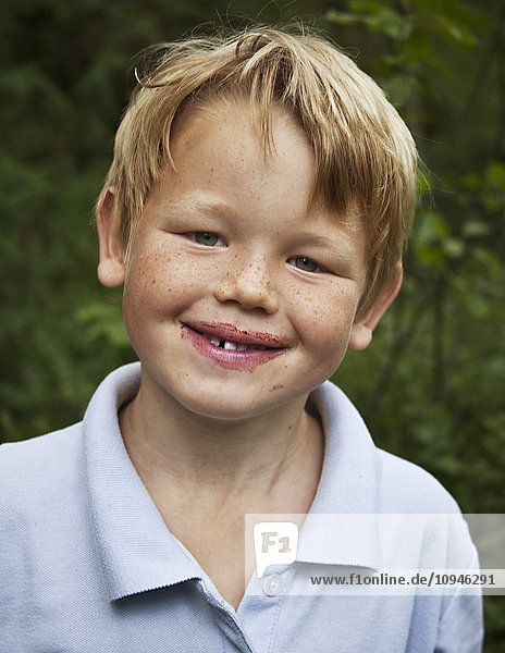 Junge mit Blaubeersaft im Gesicht  Nahaufnahme  Porträt  lächelnd