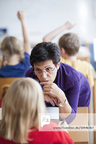 Teacher talking with schoolgirl in classroom