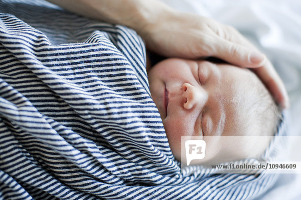 Fathers hand holding head of sleeping baby
