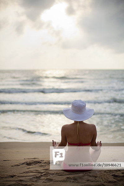 Frau meditiert am Strand
