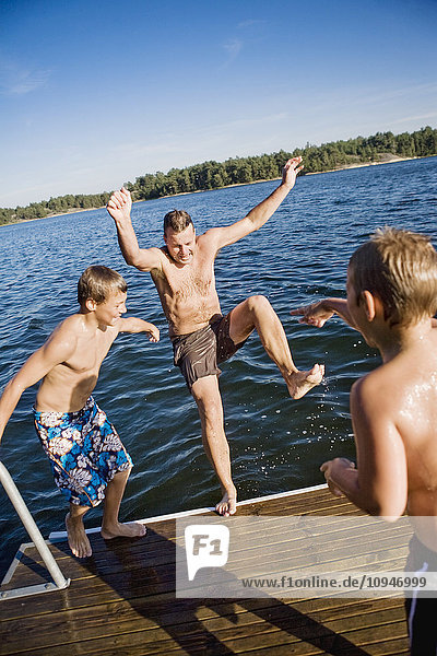 Vater spielt mit Söhnen am See