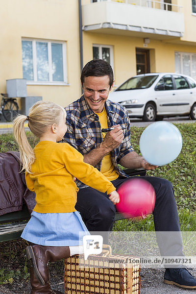 Vater mit Tochter hält Luftballons