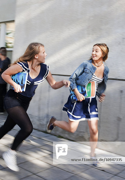 Two teenage girls running outside school