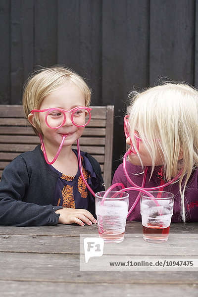 Mädchen trinken durch Strohhalmbrillen