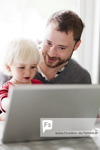Father and baby son looking at laptop