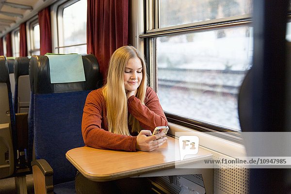 Junge Frau benutzt Mobiltelefon im Zug