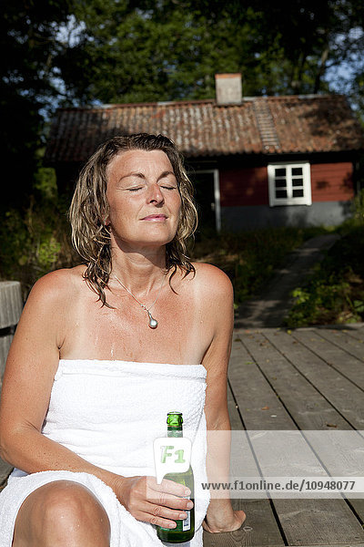 Woman wrapped in towel relaxing on deck