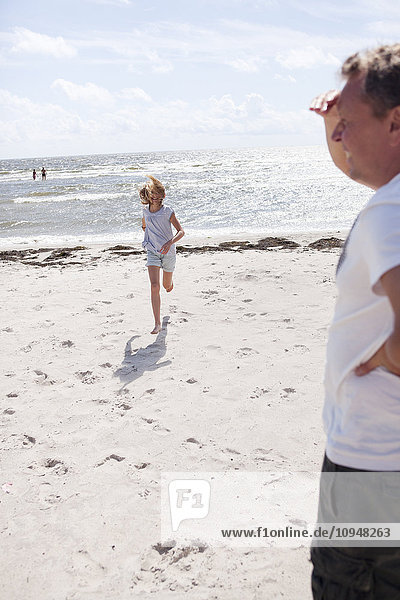 Mädchen läuft am Strand zu ihrem Vater