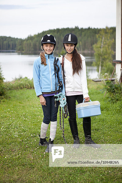 Zwei Mädchen in Jockey-Kleidung stehen auf Rasen