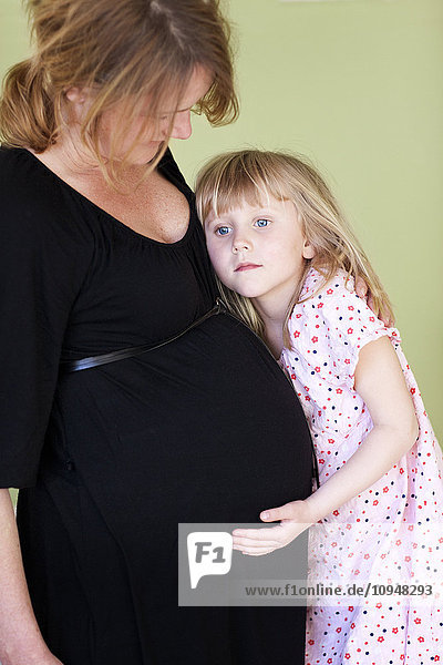 Mädchen  das seine schwangere Mutter umarmt  Studioaufnahme