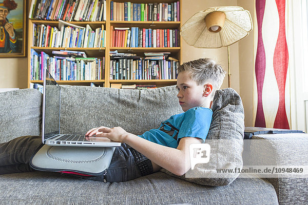 Boy using laptop on sofa