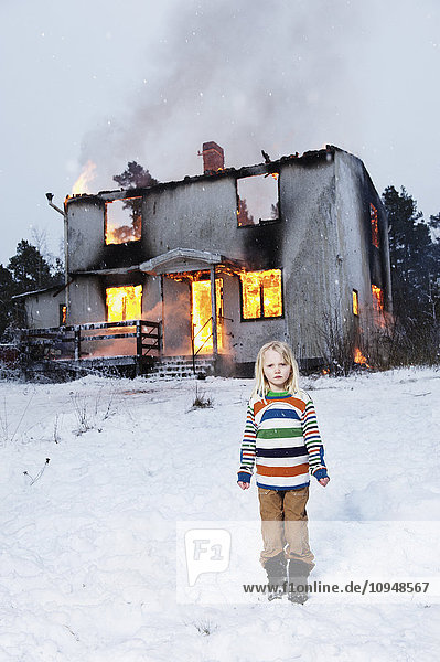 Allein stehendes Mädchen vor einem brennenden Haus