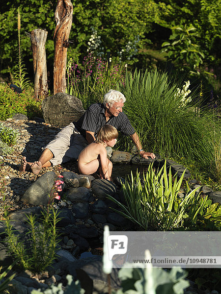 Großvater mit Enkel  der im Garten spielt