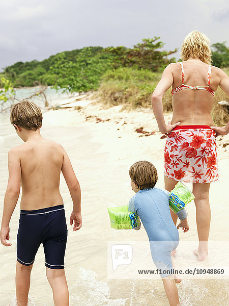 Mutter mit zwei Söhnen spazieren am Strand