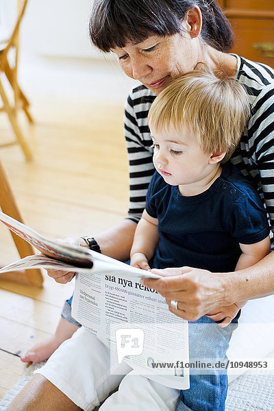 Großmutter mit Enkel beim Zeitungslesen