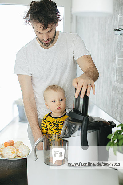 Father with baby son making orange juice