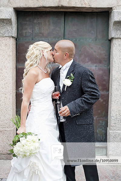 Bridal couple kissing in front of church