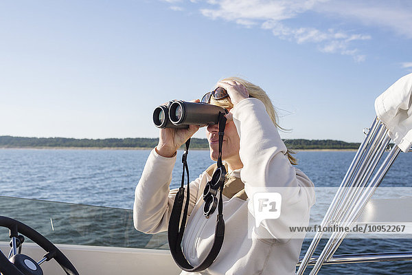 Frau auf Boot schaut durch ein Fernglas