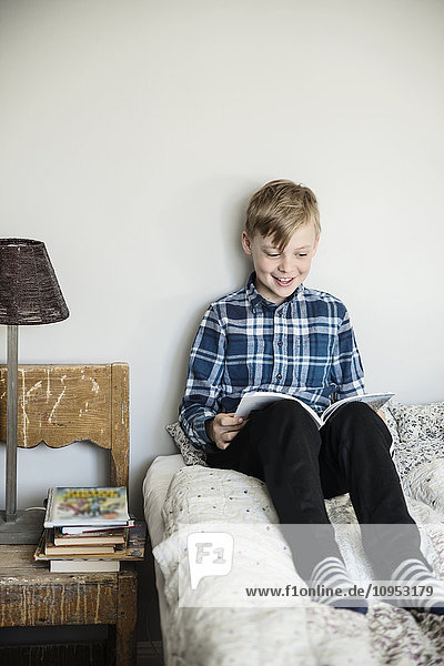 Smiling boy reading on bed
