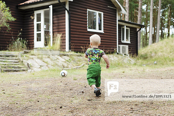 Junge spielt vor einem Haus im Wald