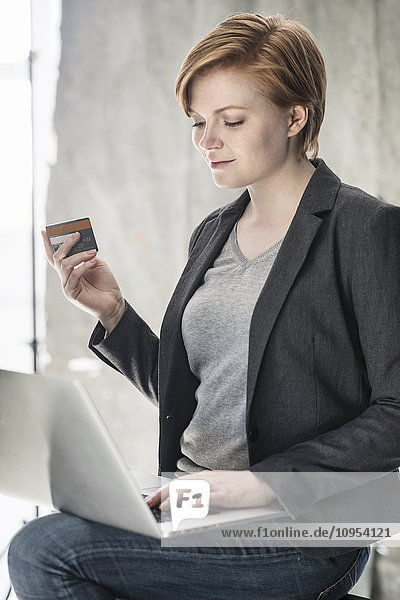 Woman with bank card using laptop