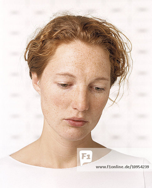 Closeup of woman looking down with white background.
