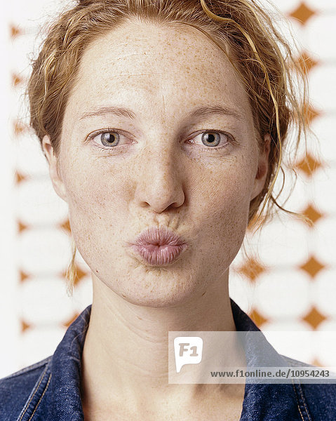 Closeup of woman with kissing mouth and white background.