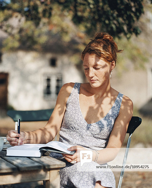 Woman in garden writing in notebook