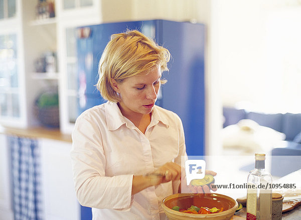 Frau in der Küche stehend und mit Gemüse arrangiert.