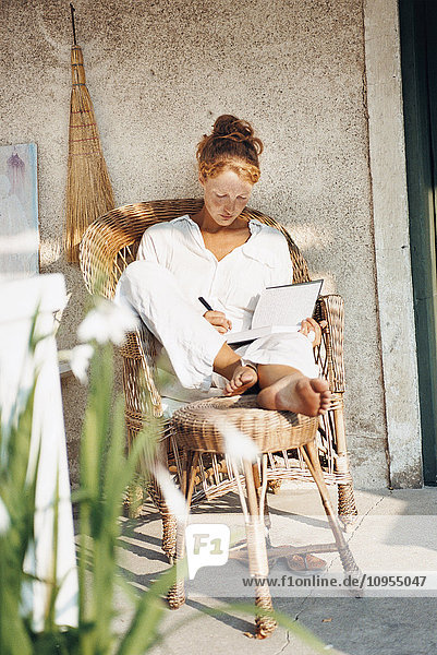 Young woman reading book in front of house