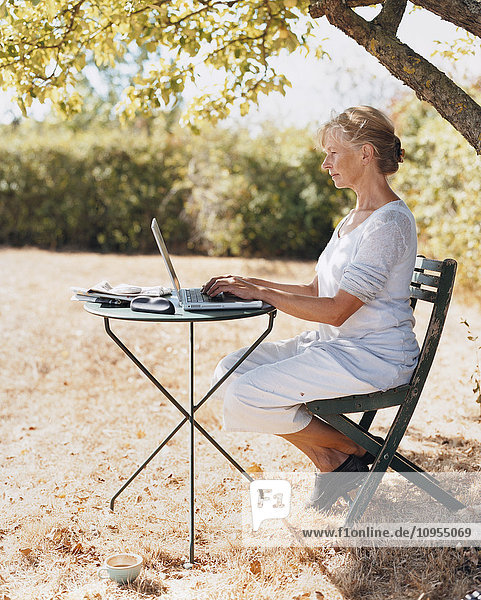 Mature woman using laptop in garden