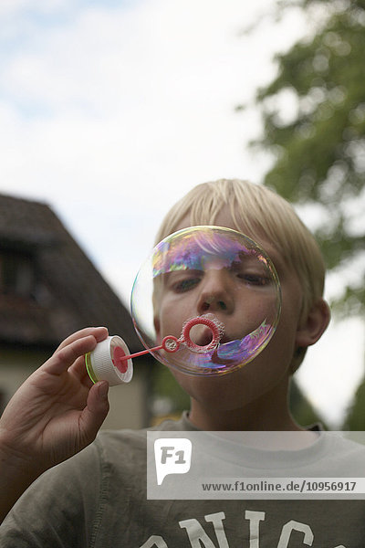 Skandinavischer Junge beim Blasen von Seifenblasen  Schweden.
