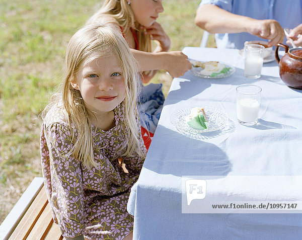 Mädchen sitzen an einem Tisch und essen Geburtstagskuchen  Schweden.