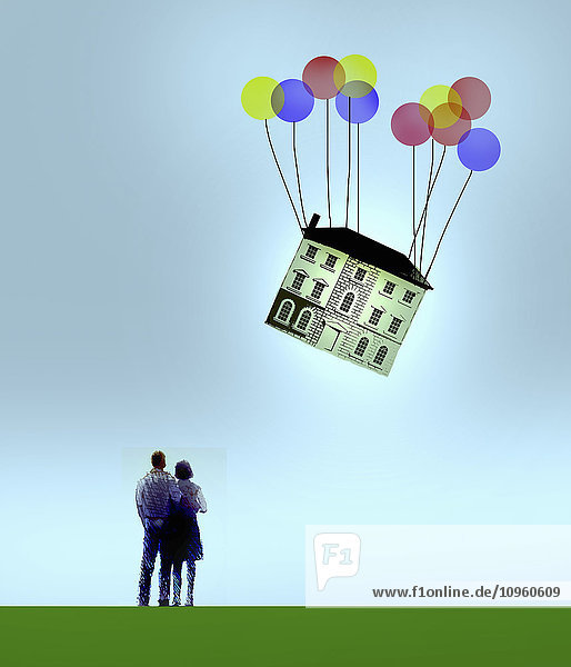 Paar schaut wegfliegendem Haus an Ballons zu
