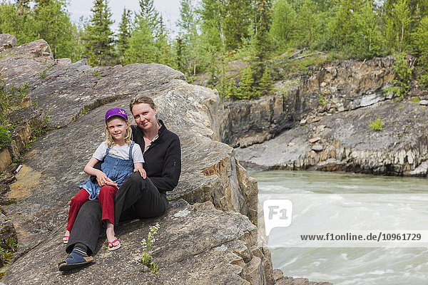 A Mother and daughter sit on top of Whirlpool Canyon along the Liard River  Alaska Highway  North of Liard Hot Springs  British Columbia  Canada  Summer