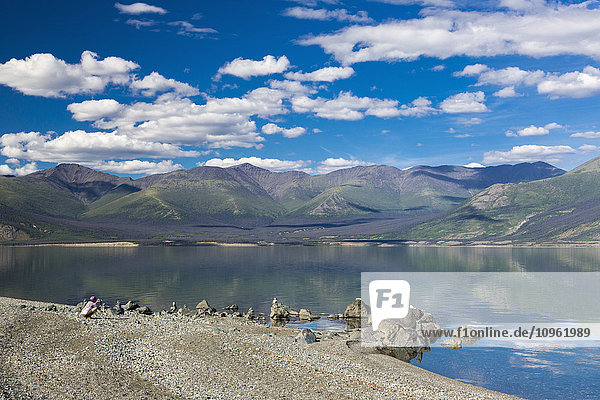 Woman photographs stacked rocks along Kluane Lake  Yukon Territory  Canada