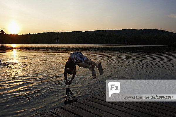 Junge taucht bei Sonnenuntergang in einen See; Lac des Neiges  Quebec  Kanada'.