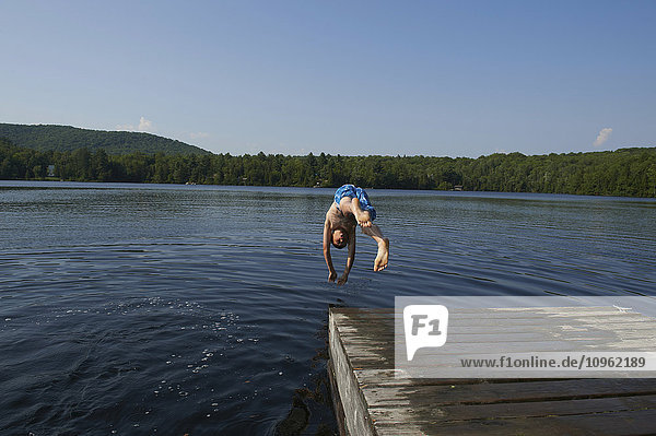 Ein Junge springt von einem Holzsteg in einen See; Lac des Neiges  Quebec  Kanada'.