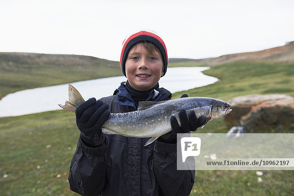 Junge hält frisch gefangenen Seesaibling in der Nähe von Cambridge Bay; Nunavut  Kanada'.
