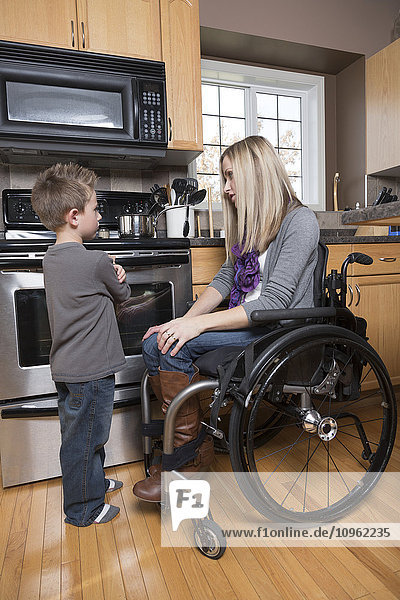 Junge behinderte Mutter im Gespräch mit ihrem kleinen Sohn in ihrer Küche; Spruce Grove  Alberta  Kanada'.