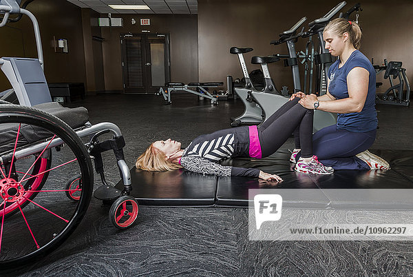 Physiotherapeutin  die einer jungen Frau mit Rückenmarksverletzung bei der Durchführung von Brückenübungen hilft; Edmonton  Alberta  Kanada