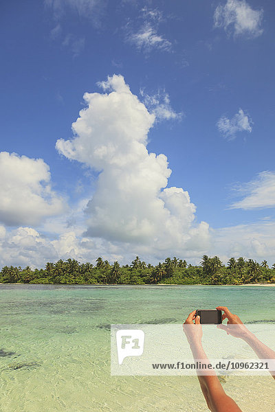 Frau fotografiert ein Atoll mit einem Smartphone; Insel Medahutthaa  Nord-Huvadhoo-Atoll  südliche Malediven'.