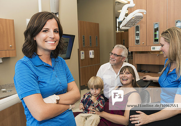'Dentist with two assistants completing a consultation with mother and son patients; Edmonton  Alberta  Canada'