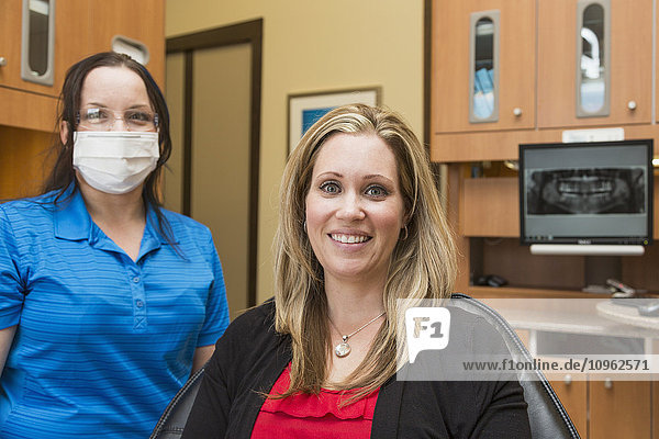 Weiblicher Patient posiert vor einer zahnärztlichen Untersuchung durch eine Zahnarzthelferin; Edmonton  Alberta  Kanada'.