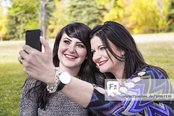 'Mother and daughter taking a selfie in a city park in autumn; St. Albert  Alberta  Canada'