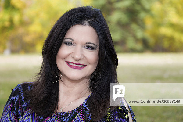'Portrait of a beautiful mature woman outdoors in a city park in autumn; St. Albert  Alberta  Canada'