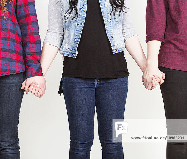 'Three young women holding hands committed to teamwork; Alberta  Canada'